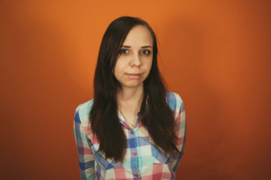 Ekose gömlekli güzel bir kadın turuncu arka planda poz veriyor..