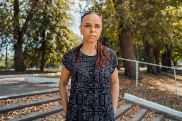 Una donna a buon mercato in una tuta nera nel parco. — Foto Stock