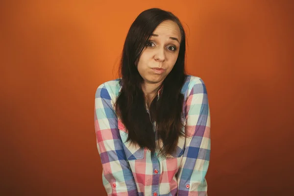 Uma mulher bonita em uma camisa xadrez posa em um fundo laranja. — Fotografia de Stock