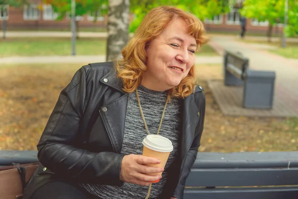 Mulher adulta bebendo café no Parque do Outono, sentado em um banco — Fotografia de Stock