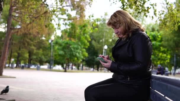 Una Mujer Adulta Sentada Banquillo Otoño Que Utiliza Teléfonos Móviles — Vídeos de Stock