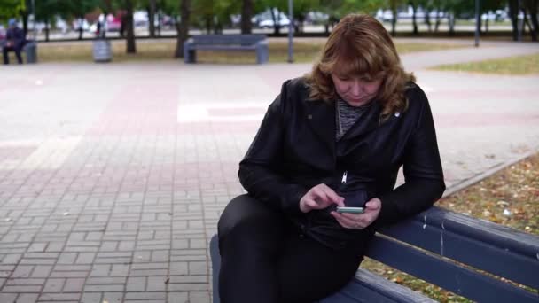 Una Mujer Adulta Sentada Banquillo Otoño Que Utiliza Teléfonos Móviles — Vídeo de stock