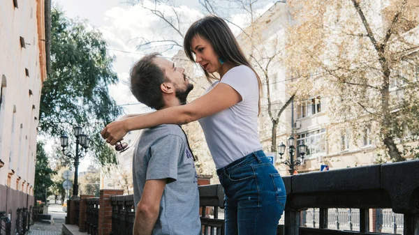 Ένα ευτυχισμένο ζευγάρι κοιταχτεί στα μάτια στο δρόμο της πόλης. Μια νεαρή γυναίκα αγκαλιάζει έναν άντρα, βάζοντας τα χέρια της στους ώμους του.. — Φωτογραφία Αρχείου