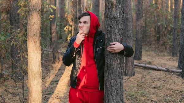 Homme debout à côté des arbres dans une journée ensoleillée. Portrait de jeune homme en vêtements décontractés posant parmi les arbres — Photo