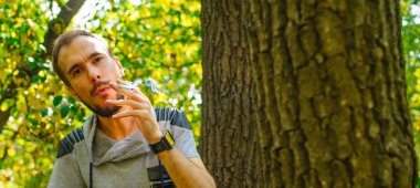 Ormanda sigara içen zayıf bir adam. Hippi parkta sigara içiyor.