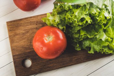 Marul ve olgun kırmızı domates dilimleme tahtasında. Taze meyve.