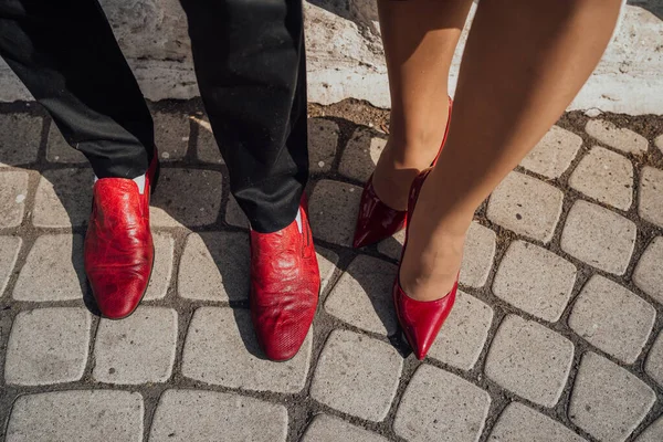 赤い靴の男性の足とかかとの赤い靴の女性の足は舗装スラブ上にあります. — ストック写真