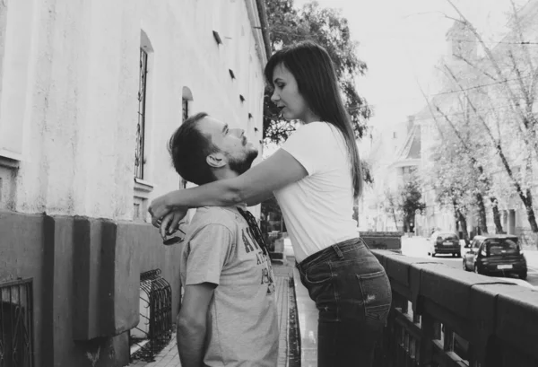 A happy loving couple look into each other's eyes in the city street. A young woman embraces a man, putting her hands on his shoulders. — Stock Photo, Image