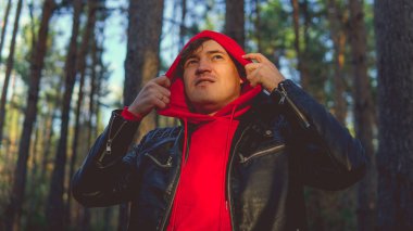 Genç yakışıklı bir adam sonbahar ormanında gün batımında yüzünü buruşturur..