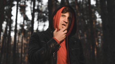 Genç yakışıklı bir adam günbatımında sonbahar ormanında poz verir.