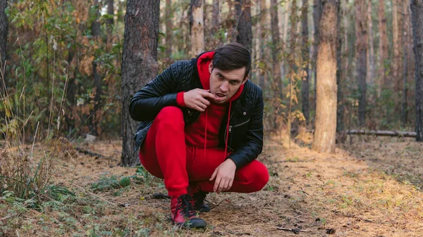 Un jeune et bel homme grimace dans la forêt d'automne au crépuscule. — Photo