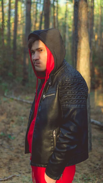 A young handsome man poses in the autumn forest at sunset — Stock Photo, Image