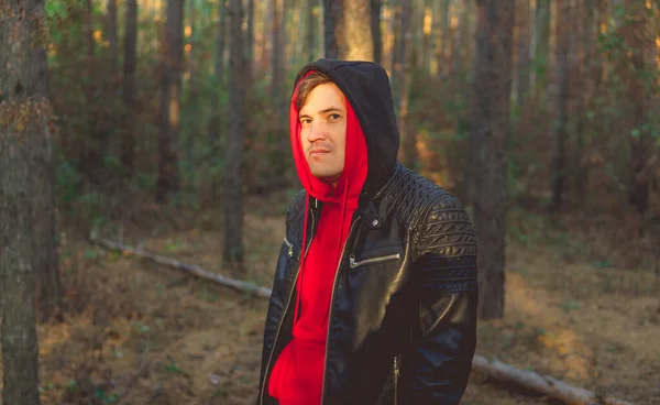 Un jeune bel homme pose dans la forêt d'automne au coucher du soleil — Photo