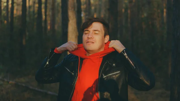 Un joven guapo se levanta en el bosque de otoño al atardecer. — Foto de Stock