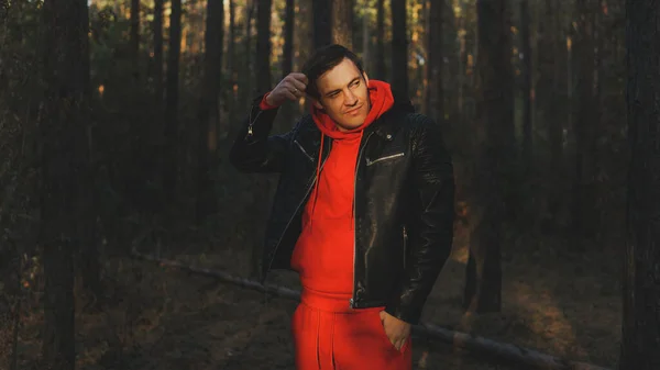 Un jeune bel homme pose dans la forêt d'automne au coucher du soleil — Photo