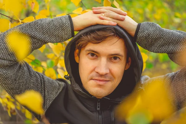 Sonbahar ormanındaki sarı ağaçlara karşı günlük giysiler içinde genç yakışıklı bir adamın portresi.. — Stok fotoğraf