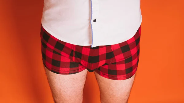 Man lichaam in de geruite boxers en in wit shirt op oranje achtergrond. — Stockfoto