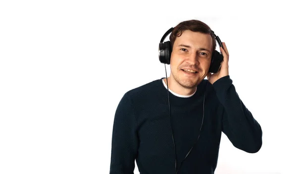 Schöner junger Mann mit Kopfhörern tanzt isoliert auf weißem Hintergrund. Das Konzept des Internationalen Tages der Musik. — Stockfoto