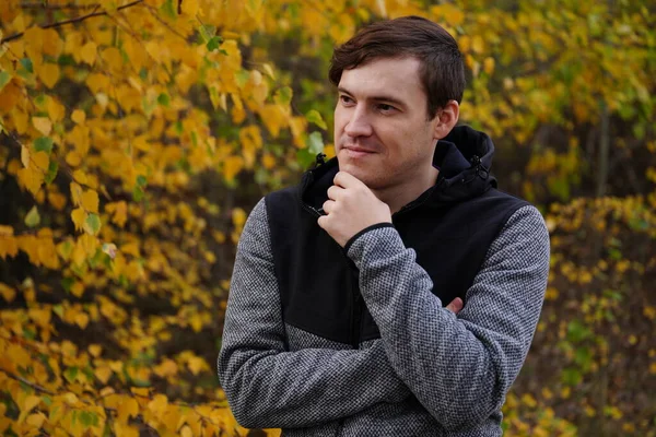 Retrato de un joven guapo vestido de forma casual contra los árboles helados del bosque de otoño.. — Foto de Stock