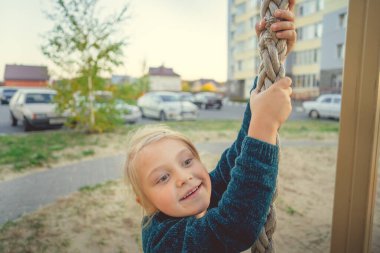 İple gezen gülümseyen kız. Çekici, neşeli esmer kız gözleri kapalı parkta oyun parkında iple geziyor.