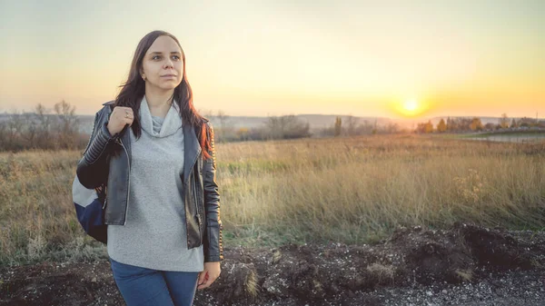 Una bella giovane donna è in campo sullo sfondo del tramonto. — Foto Stock