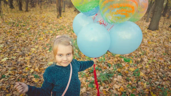秋の森の中で風船を抱えている女の子. — ストック写真