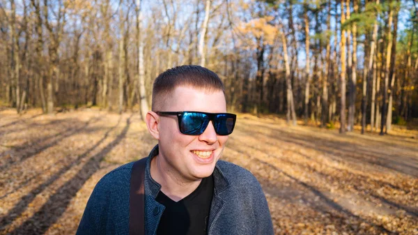 A man in sunglasses poses in the autumn forest — Stock Photo, Image