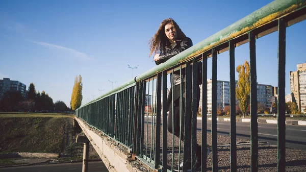 在市区的背景下，一位年轻貌美的妇女若有所思地站在桥上. — 图库照片