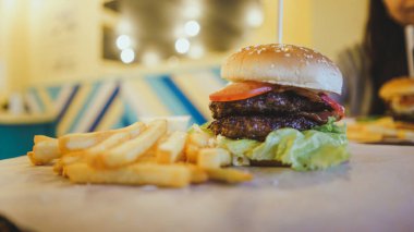 Sulu hamburger, iki pirzola ve patates kızartması. Lezzetli kocaman bir hamburger. Fast food konsepti, lezzetli ama sağlıksız..