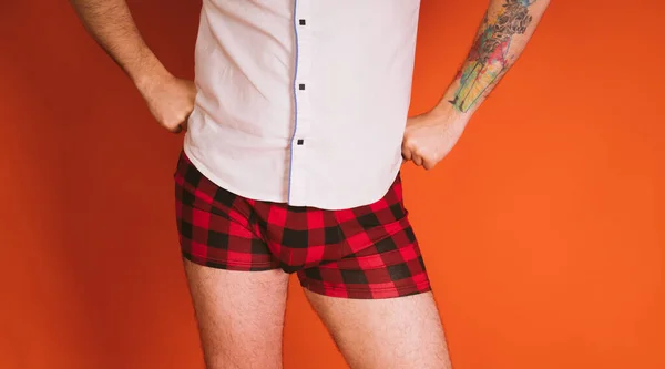 Man lichaam in de geruite boxers en in wit shirt op oranje achtergrond. — Stockfoto