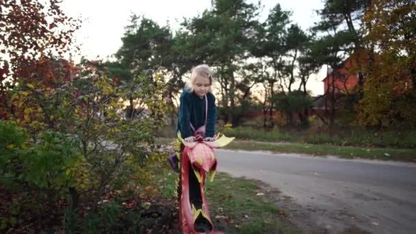 Чарівна дівчинка в повсякденному одязі сидить на структурі кольорових шин у сільській місцевості . — стокове відео