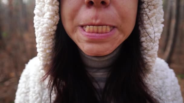En ung kvinna apar i skogen. Hon öppnar munnen och visar tänderna. Närbild. — Stockvideo