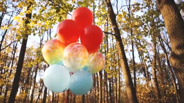 Les ballons colorés se développent dans le vent de la forêt automnale. — Video