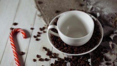 Bir fincan sıcak kahve, şekerli ve kahve çekirdekleri bir kafede masanın üzerinde. Lezzetli bir kahve ve tatlı bir atıştırmalık..