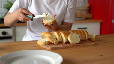 Erimiş peynirle dilimlenmiş ekmek yayan bir kadın. Mutfakta sandviç hazırlayan kadınların ellerini kapat..