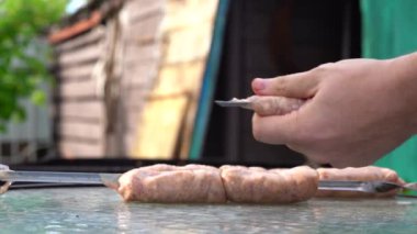 Adam şişe çiğ sosis sokuyor. Erkeklerin ellerini sosisli sandviçle tutun. Açık hava pikniği kavramı.
