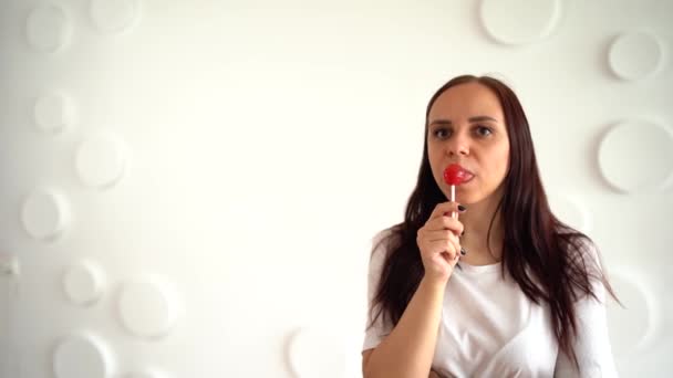 Mujer Joven Lamiendo Grandes Lollipop Contra Pared Blanca Patrullada Cierre — Vídeo de stock