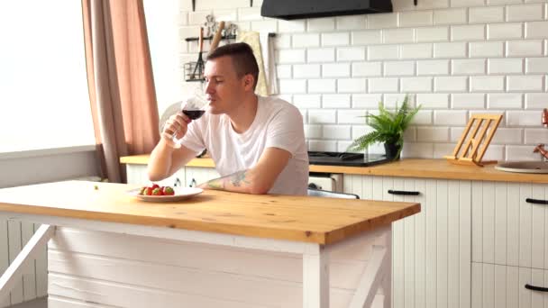 Młody Człowiek Pije Czerwone Wino Siedzi Przy Kuchennym Stole Dorosły — Wideo stockowe