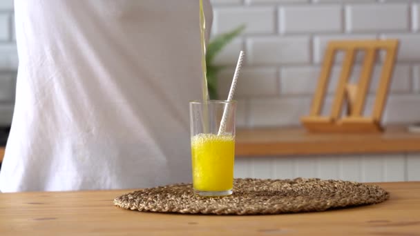オレンジレモネードをグラスに注ぐ女性 キッチンでソーダで透明なガラスを充填の閉じる — ストック動画