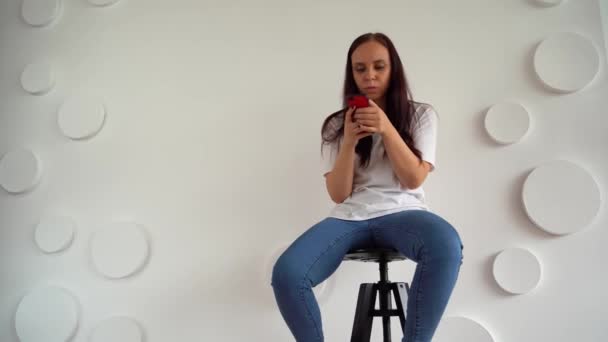 Молодая Женщина Листает Чат Смартфоне Фоне Белой Узорчатой Стены Взрослые — стоковое видео