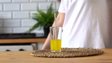 Mutfakta bir bardak limonata içen bir kadının elini kapat. Portakallı gazoz içen kadın susuzluğunu gideriyor..
