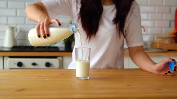 牛乳をグラスに注ぐ女性 キッチンでボトルから便利な飲み物で透明なガラスを充填女性の手の閉じる — ストック動画