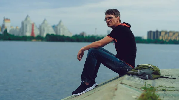 Retrato Homem Óculos Roupas Casuais Sentado Junto Rio Dia Nublado — Fotografia de Stock