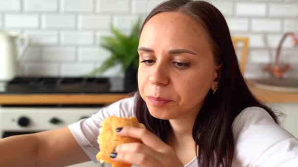 若い女性のキッチンでバーガーを食べるのを閉じる 大人の女性は朝早く朝食を食べ — ストック動画