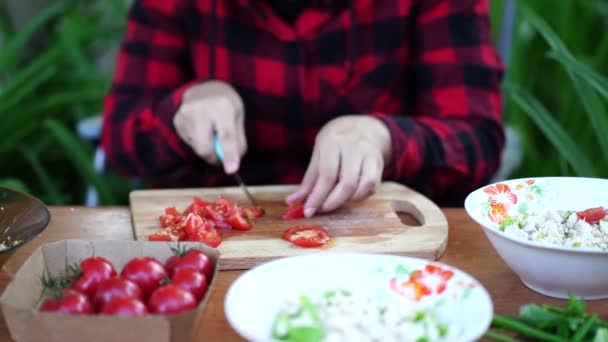 Mujer cortando tomates en tablero de madera al aire libre. Primer plano de las manos de las mujeres de corte vegetal con cuchillo en la tabla de cortar . — Vídeos de Stock