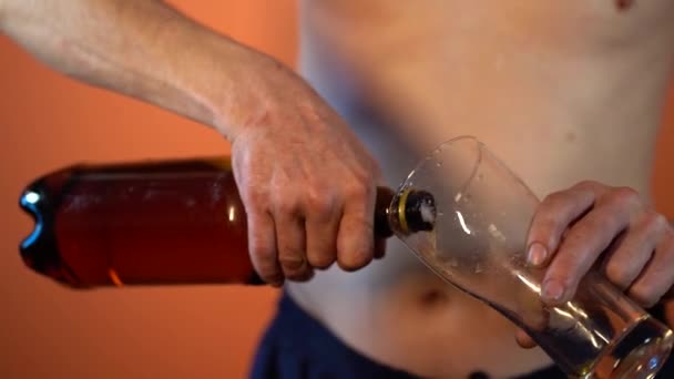 一个成熟的男人 赤身裸体地从瓶子里倒啤酒到杯子里 紧紧抓住男人的手 用酒精灌满透明的玻璃杯 — 图库视频影像