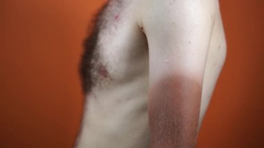 Güçlü bronz tenli bir adamın eline yaklaş. Beyaz çıplak erkek vücudu ve yarım bronzlaşmış el..