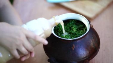 Kadının elleri kapalıyken tencereye kvass döker. Kadın soğuk çorba hazırlıyor - okroshka.