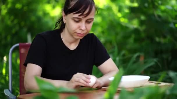 Νεαρή Γυναίκα Ξεφλουδίζει Βραστό Αυγό Κάθεται Στο Τραπέζι Στον Κήπο — Αρχείο Βίντεο