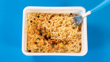 Baharatlı ve çatallı hazır erişteleri mavi arkaplanda yakın çekim yapın..